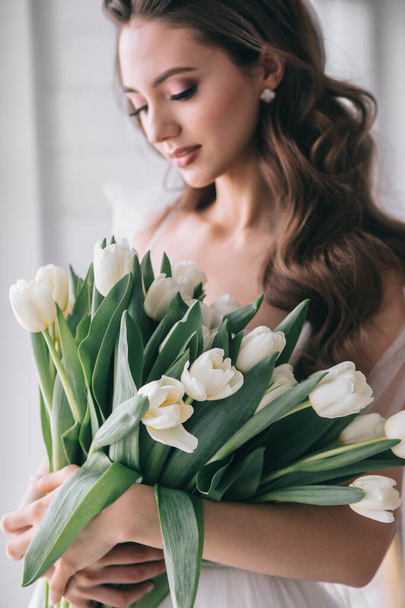 Wedding bouquet of white tulips in the hands of a beautiful bride indoor. Selective soft Focus - Foto, Imagen