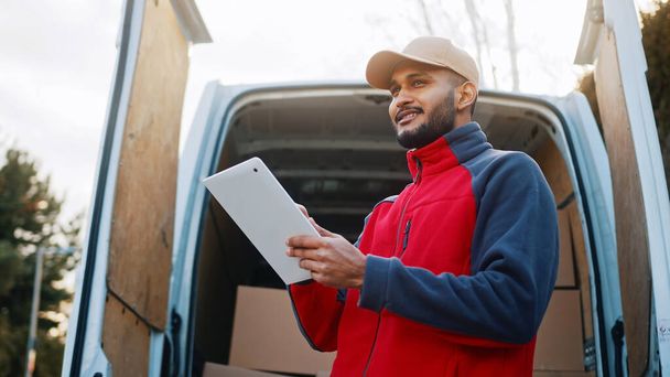 Courier with digital tablet delivering package. Mailman in front the van - Fotó, kép