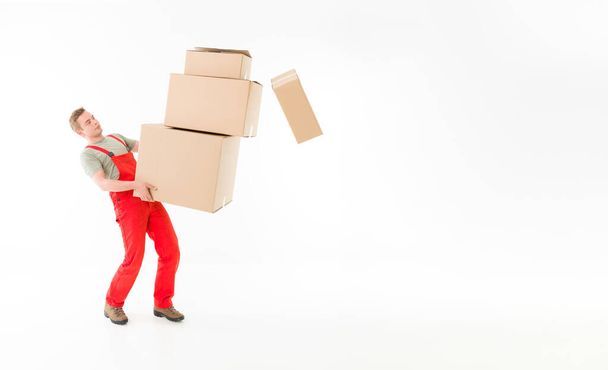 delivery man carrying pile of boxes and dropping some of them, isolated on white background - Photo, Image