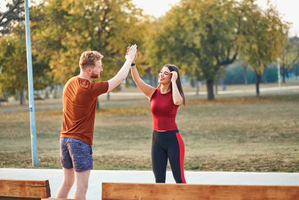 Two young sporty man and woman exercising in urban park. - Photo, Image