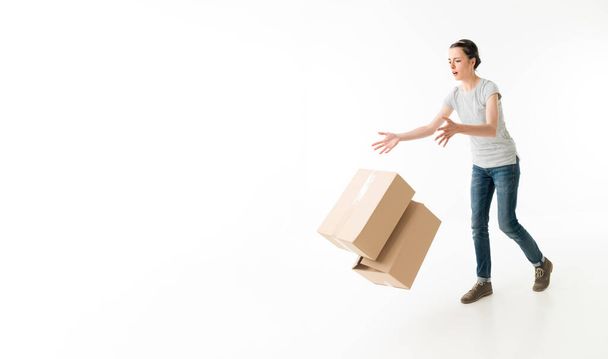 neohrabaná mladá žena upustí pohyblivé krabice a zakopne. na bílém pozadí - Fotografie, Obrázek