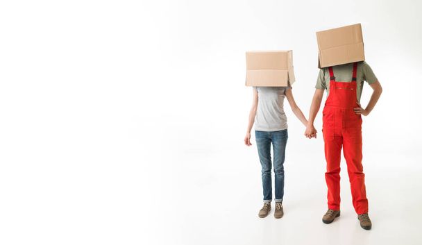 giovane coppia con scatole di cartone in testa, tenendosi per mano, su sfondo bianco - Foto, immagini