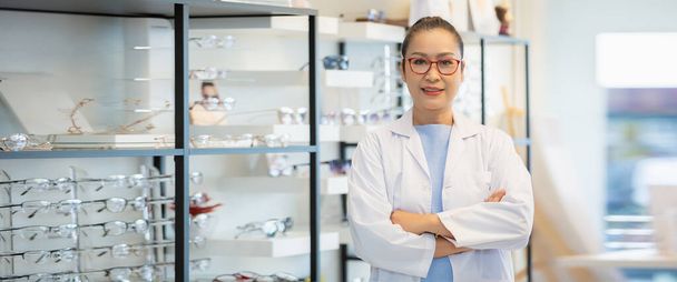 portrait of asian women middle age opticians optometrists wear glasses and uniform crossed arms standing in optical shop. image banner. - Photo, image