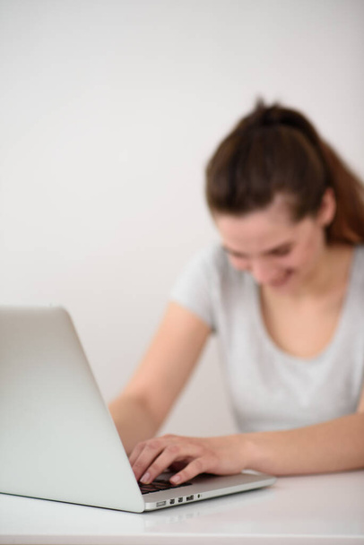 La chica está fuera de foco sentada en la computadora y riendo. Cabeza inclinada hacia abajo. Bloger - Foto, imagen