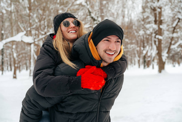 Happy couple hugging and smiling outdoors in snowy park - Фото, изображение