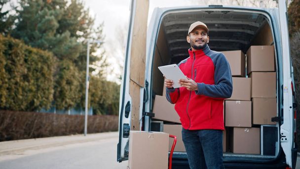 Courier with digital tablet delivering package. Mailman in front the van - Foto, imagen
