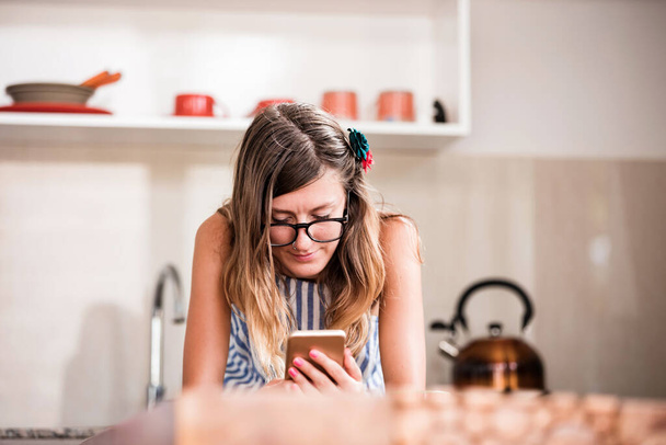 Young adult woman using smartphone in a modern home. - Fotografie, Obrázek