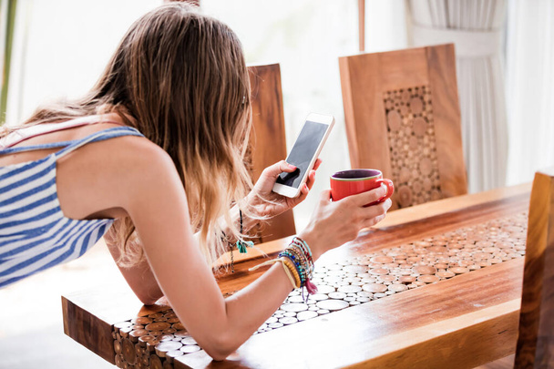 Giovane donna adulta che utilizza lo smartphone in una casa moderna. - Foto, immagini