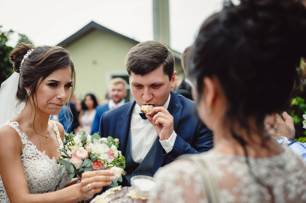 Gelin ve damadın geleneksel somun yerken yakın plan fotoğrafı. Ukrayna ve Rusya 'nın düğün töreni: tuzlu düğün ekmeği. - Fotoğraf, Görsel