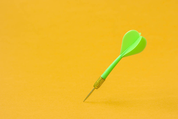 Green dart arrow on the yellow background. Copy space. - Фото, изображение