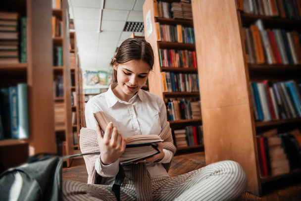 education, high school, university, learning concept - smiling student girl reading book at library - Φωτογραφία, εικόνα