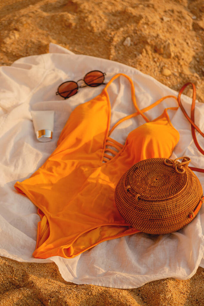 Beautiful female yellow swimsuit, glasses and cream on the beach. - Photo, Image