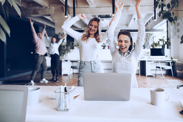 Two young happy businesswomen celebrating project success in office - Φωτογραφία, εικόνα