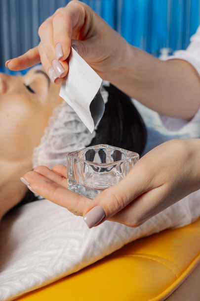 Professionelle Kosmetikerin gießt Puder in eine Glasschüssel. - Foto, Bild
