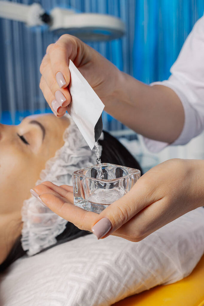 Mujer esteticista profesional vierte polvo en un recipiente de vidrio. - Foto, imagen