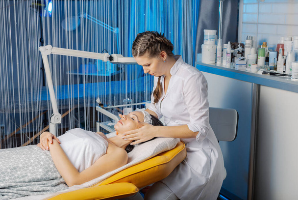 Professional beautician makes a facial massage to a woman. - Zdjęcie, obraz