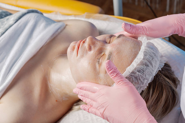 Professional beautician makes a facial massage to a woman. - Φωτογραφία, εικόνα