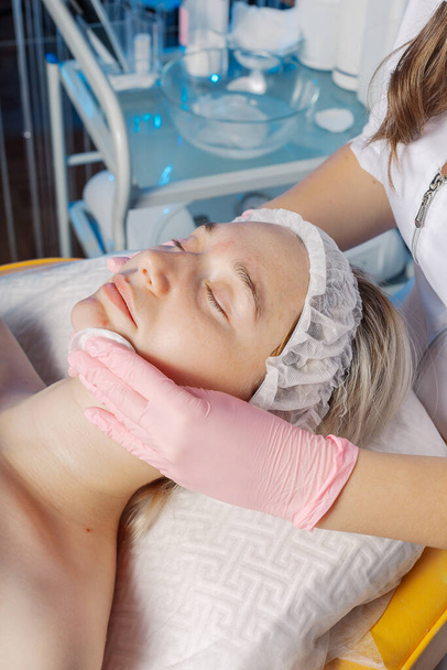 esteticista profesional limpia una cara de mujer después del procedimiento. - Foto, imagen