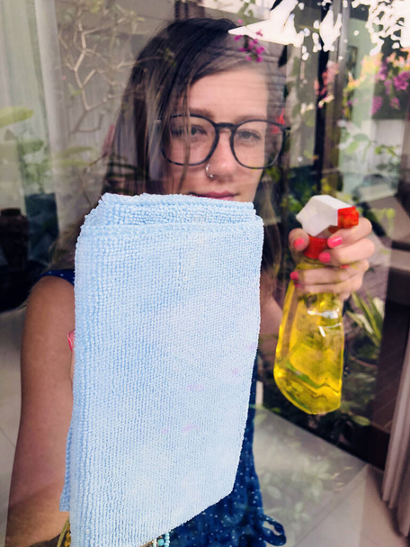 Mulher segurando pano e detergente para limpar a janela. - Foto, Imagem