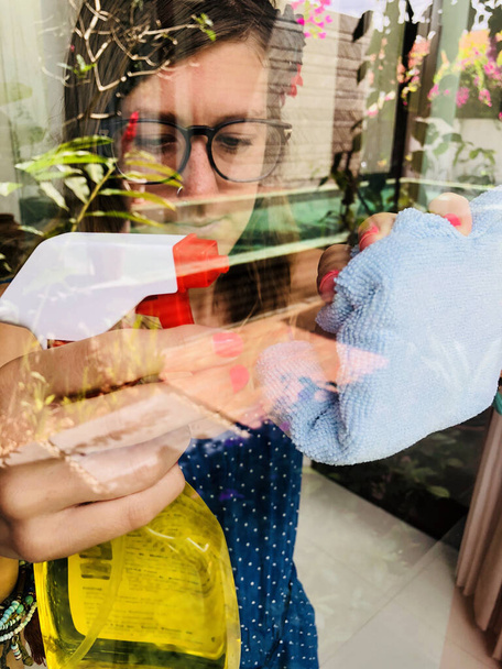 Nő kezében rongy és mosószer tisztítására az ablak. - Fotó, kép
