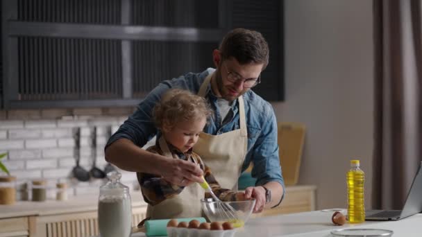 Mann und kleiner Junge schlagen Eier für Omelett, Vater lernt Sohn Kochen in der heimischen Küche und verbringt Zeit miteinander - Filmmaterial, Video