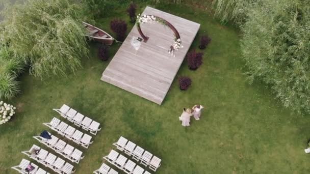 Widok z lotu ptaka i ozdobiony trawnik z krzesłami do ceremonii ślubnej na brzegu rzeki - Materiał filmowy, wideo