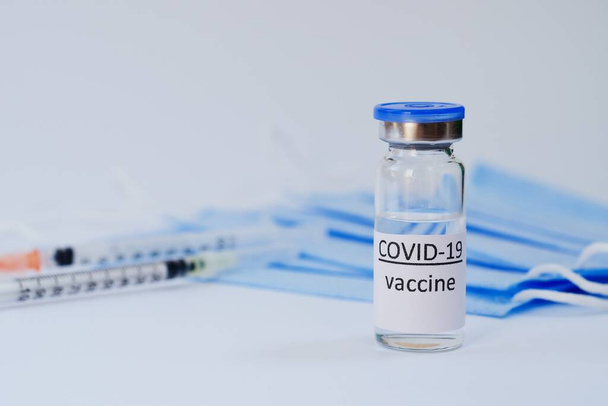 Aşı konseptinin yaratıcı fikirleri. Tıbbi maskeli şırınga ve aşı şişeleriyle COVID-19 'a karşı aşı için en iyi görüntü. Koronavirüs salgını. Boşluğu kopyala.  - Fotoğraf, Görsel