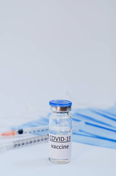 Kreative Ideen für ein Impfkonzept. Draufsicht der Spritze mit medizinischen Masken und Glasflaschen für Impfflaschen zur Impfung gegen COVID-19. Coronavirus-Pandemie. Kopierraum.  - Foto, Bild