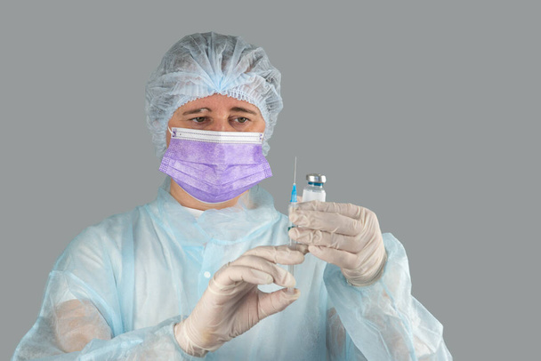 νοσοκόμα με μια σύριγγα στο χέρι και μια φύσιγγα με εμβόλιο κατά της ιογενούς νόσου - Φωτογραφία, εικόνα
