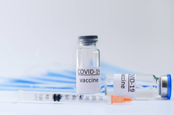 Kreative Ideen für ein Impfkonzept. Draufsicht der Spritze mit medizinischen Masken und Glasflaschen für Impfflaschen zur Impfung gegen COVID-19. Coronavirus-Pandemie. Kopierraum.  - Foto, Bild