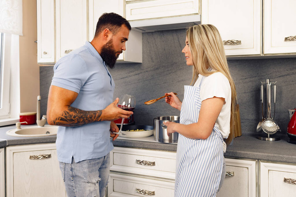 Young man and woman cooking food in kitchen together, happy couple preparing food - Foto, Imagen