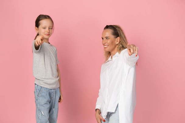 Δύο άτομα, νεαρή γυναίκα και μικρό κορίτσι απομονωμένα σε ροζ φόντο. - Φωτογραφία, εικόνα