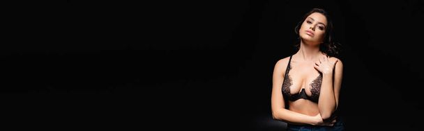 брюнетка сексуальная женщина в кружеве бюстгальтер глядя на камеру изолированы на черный, баннер - Фото, изображение