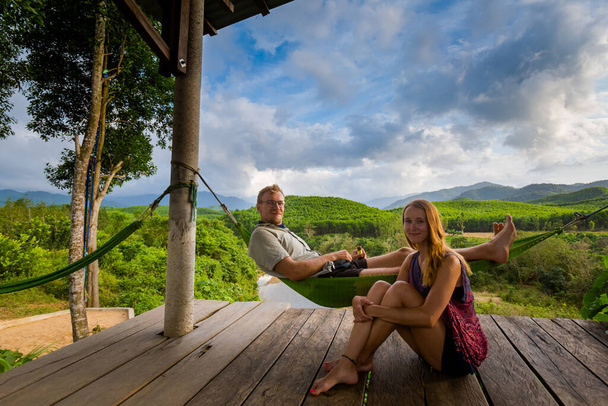 Belos jovens turistas caucasianos casal relaxando em uma rede no Parque Nacional Phong Nha Ke Bang, Vietnã. Paisagem rural foto tirada no sudeste da Ásia - um dos lugares mais bonitos vietnamitas. - Foto, Imagem