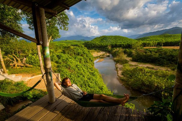 Bela jovem turista caucasiano relaxante em uma rede no Parque Nacional Phong Nha Ke Bang, Vietnã. Paisagem rural foto tirada no sudeste da Ásia - um dos lugares mais bonitos vietnamitas. - Foto, Imagem