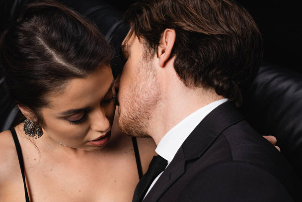 uomo appassionato in tuta baciare donna sexy sul nero - Foto, immagini