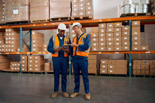 Multiracial male factory worker checking the orders in digital tablet at large warehouse - Foto, imagen