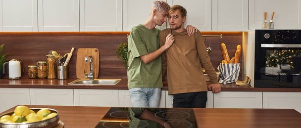 Homosexual male pair hugging while standing on kitchen - Fotoğraf, Görsel