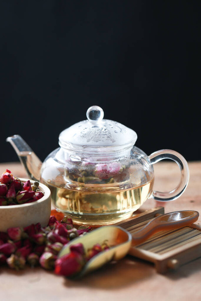 Rose tea with transparent glass and jug with dried rose flower on wood board. Aroma rose hot drink  for healthy  by flower tea. - Photo, Image