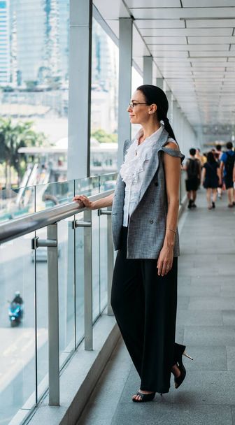 Business woman standing at sky walk and looking at city - Foto, imagen