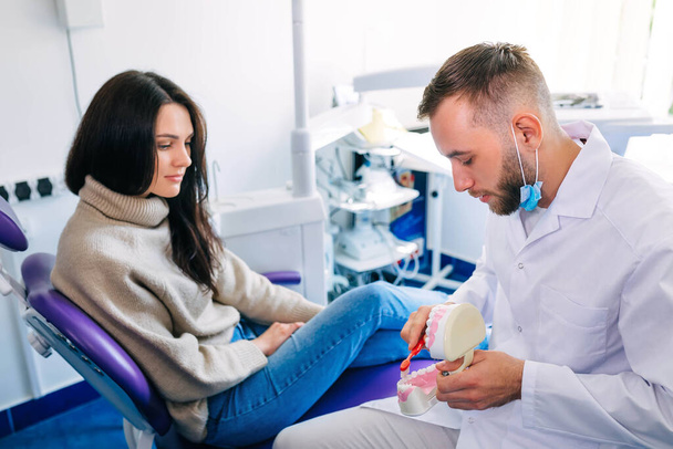 οδοντίατρος δείχνουν πώς να βουρτσίζετε τα δόντια σας σωστά στον ασθενή. οδοντιατρείο. - Φωτογραφία, εικόνα