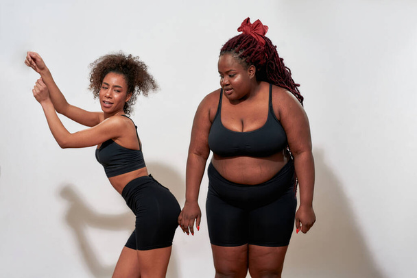 Two afro women with S and XXl size standing over the wall - Foto, imagen