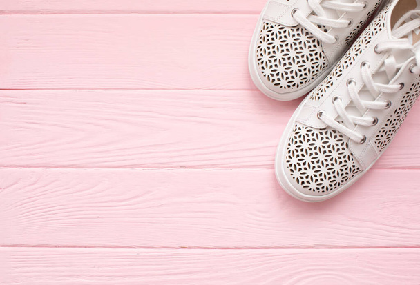 top view of white stylish shoes on pink wooden background with copy space   - Фото, зображення
