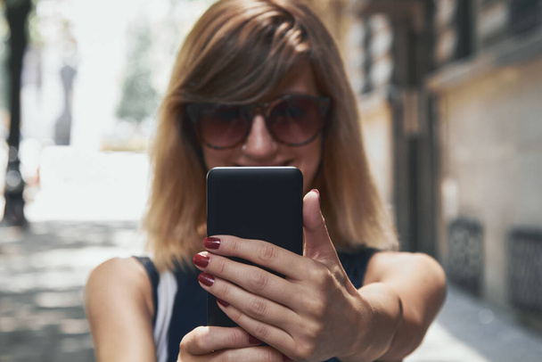 Жінка використовує сучасний смартфон на вулиці
. - Фото, зображення