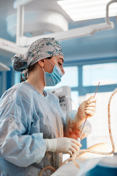 cirugía de liposucción cosmética en quirófano real mostrando el grupo de cirujanos durante la operación - Foto, Imagen
