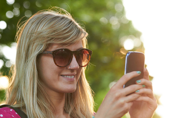 fiatal nő használó modern okostelefon szabadban. - Fotó, kép