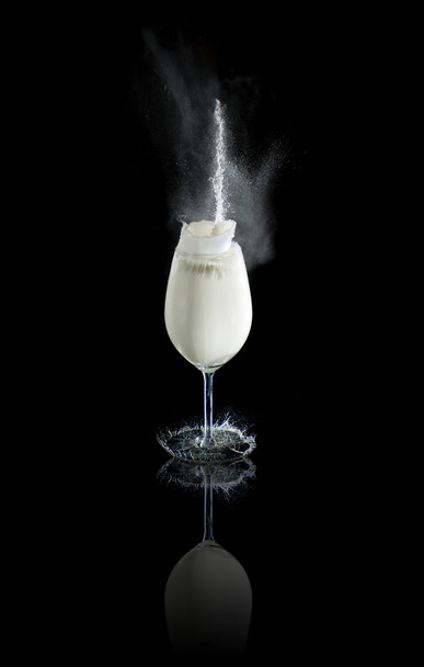 Glass of milk with splashes at black background - Foto, afbeelding