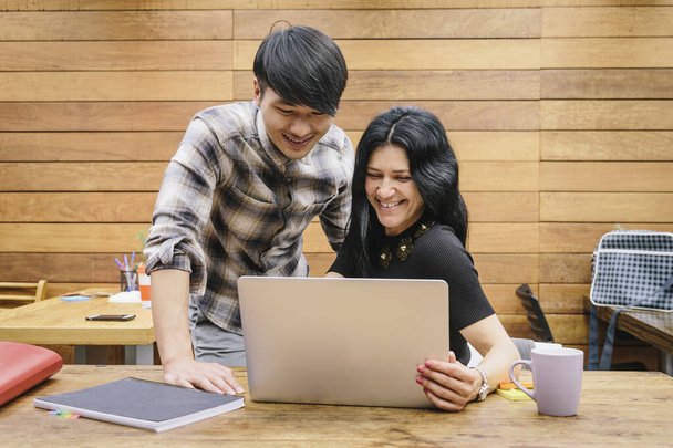 Couple multiethnique travaillant dans un espace de coworking moderne avec un ordinateur portable - Photo, image