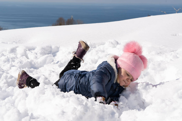 Lány fekszik a hóban télen - Fotó, kép