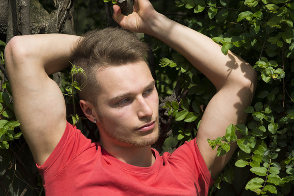 Attractive young blond man against wall of green ivy - Φωτογραφία, εικόνα